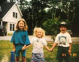 three children holding hands on a lawn